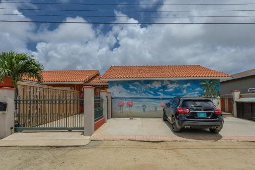 a car parked in front of a house with a mural at Moderne Studio Sea dichtbij de zee met zwembad in Oranjestad