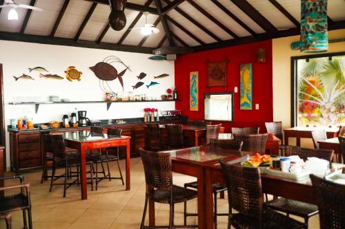 a restaurant with red walls and tables and chairs at Pousada é in Cumuruxatiba