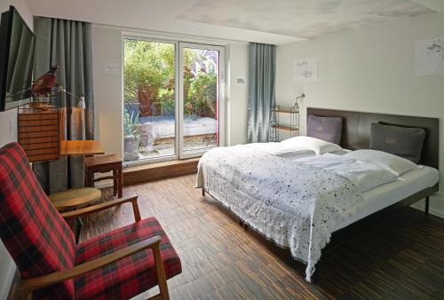 a bedroom with a bed and a chair and a window at Das kleine Schwarze - Bed & Breakfast in Hamburg