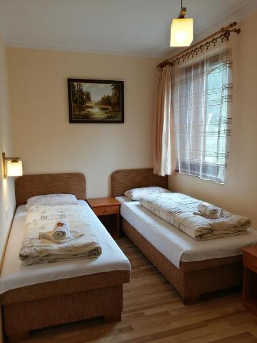 two beds in a room with a window at Penzión pod Barancom in Žiar