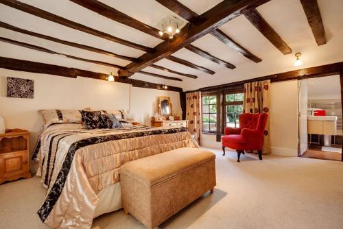 um quarto com uma cama grande e uma cadeira vermelha em The Greyhound - Historic former Inn em Glemsford