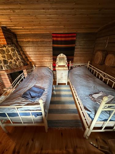 two beds in a room with wooden walls at Saimaa Lakeside Sauna Cabin in Taipalsaari