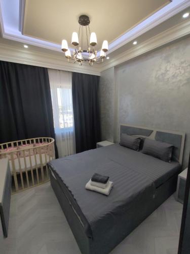 a bedroom with a king sized bed and a chandelier at Tashkent city Gardens E 8-73 in Tashkent