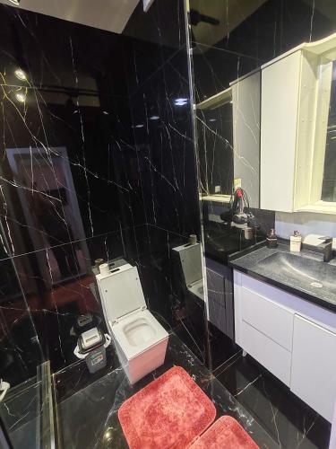 a black tiled bathroom with a toilet and a sink at Tashkent city Gardens E 8-73 in Tashkent