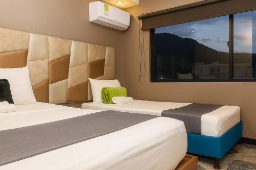 two beds in a room with a window at HOTEl AIRPORT PEREIRA in Pereira
