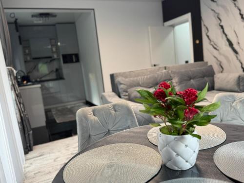 a table with plates and a vase with flowers on it at HERA Elysium Apartament AFRODITA in Sinaia