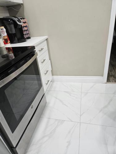 a kitchen with a stove and a white tile floor at Beautiful 3 bedrooms, 2 bathrooms, 4 beds sleep 8, basement close to Falls in Niagara Falls