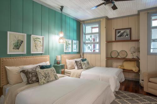 AQUIARES COFFEE FARM CASA HACIENDA LA ESPERANZA في توريالبا: سريرين في غرفة ذات جدران خضراء