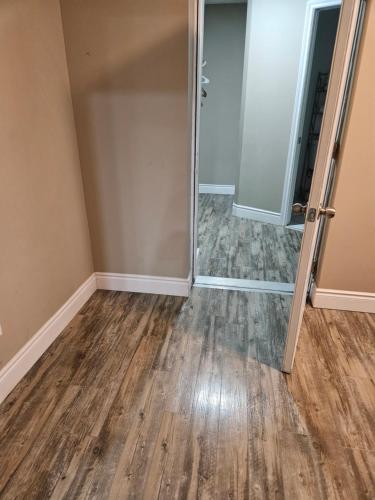 an empty room with a door and wood floors at Beautiful 3 bedrooms, 2 bathrooms, 4 beds sleep 8, basement close to Falls in Niagara Falls