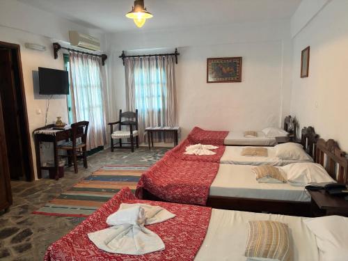 a bedroom with two beds and a desk and a piano at Arolithos Traditional Village Hotel in Tílisos