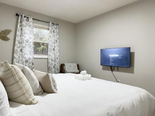 a bedroom with a large white bed with a flat screen tv at Cozy Retreat - Homes near Wesselman Park in Evansville