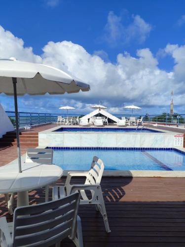 a swimming pool with chairs and umbrellas next to a swimming pool at Flat completo 50m da Praia de Tambaú com vista Mar no Terraço e Piscina in João Pessoa