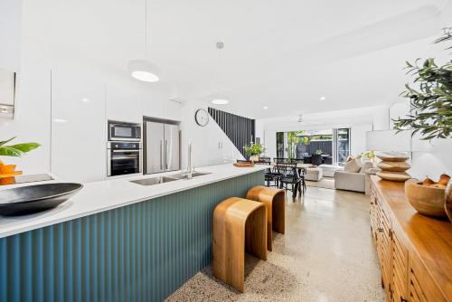 a kitchen and living room with a counter and chairs at Riverbreeze - Close to Hastings 3 bed AC Pool in Noosa Heads