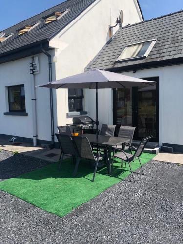 a table with an umbrella and chairs on grass at Fabulous 4 Bedroom House, Gateway to Connemara in Galway