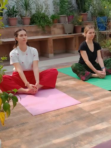 two girls sitting on mats in a yoga class at The Hideout Agra - Garden Homestay near Taj in Agra