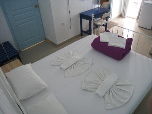 a white bed with white pillows and bows on it at Cavo Christo in Petra