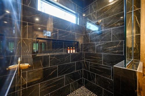 a bathroom with a shower with black tiles at Jam, Swim, Play - Pool, Hot Tub, Ping Pong, Arcade in Broken Bow