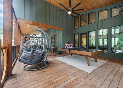 a room with a ping pong table on a wooden floor at Jam, Swim, Play - Pool, Hot Tub, Ping Pong, Arcade in Broken Bow