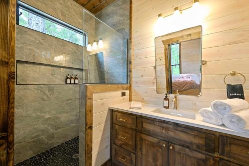a bathroom with a shower and a sink and a mirror at Jam, Swim, Play - Pool, Hot Tub, Ping Pong, Arcade in Broken Bow
