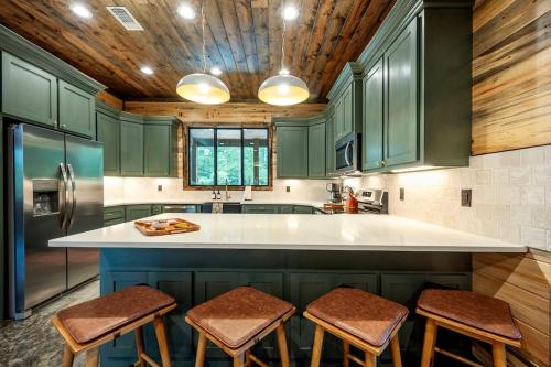 a kitchen with green cabinets and a kitchen island with stools at Jam, Swim, Play - Pool, Hot Tub, Ping Pong, Arcade in Broken Bow