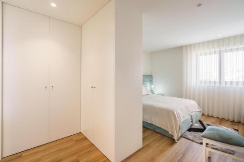 a bedroom with white walls and a bed and a window at Praia Mar Apartamento T2 in Esposende