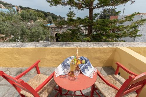 a red table with two chairs and a drink on it at Arolithos Traditional Village Hotel in Tílisos