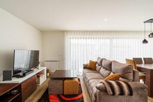 a living room with a couch and a flat screen tv at Praia Mar Apartamento T2 in Esposende