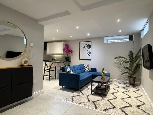 a living room with a blue couch and a kitchen at Central Bury Apartment with Private Entrance in Bury Saint Edmunds