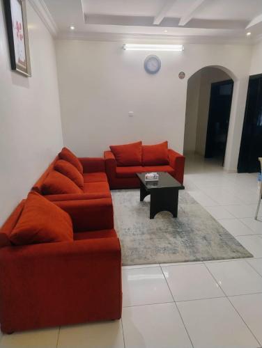 a living room with a red couch and a coffee table at ليالي البحرية للشقق المخدومة in Al Baha