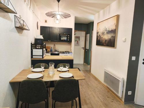 a dining room with a table and chairs and a kitchen at Le Cocon Pyrénéen - Ski aux pieds & Parking Privé in Les Angles