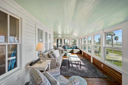 a living room with a couch and chairs and windows at Ivey House by Coastline Vacation Rentals in Saint Joe Beach