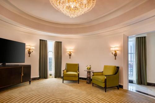 a room with two chairs and a tv and a chandelier at Willard InterContinental Washington by IHG in Washington