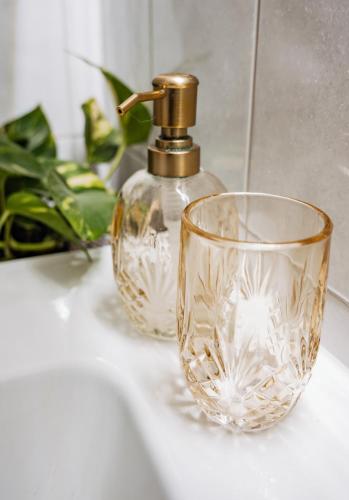 a bathroom sink with a glass cup and a faucet at Cozybude #mitliebezumdetail in Appen