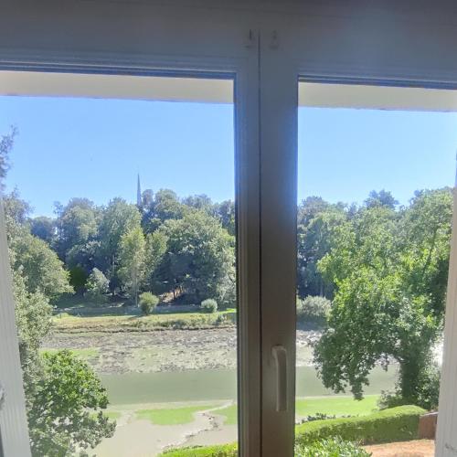 a window with a view of a field at Appartement entier, vue sur rivière & cathédrale. in Plouguiel