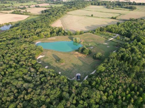 an aerial view of a lake in the middle of a forest at The Goose In The Woods - With Lakeside Sauna in Wellesbourne Hastings