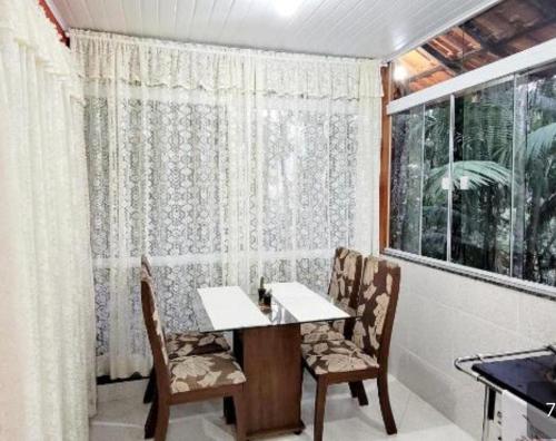 a dining room with a table and chairs and a window at Refúgio Sereno in Nova Friburgo