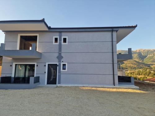 a white house with a hill in the background at Apelistra Rooms in Himare