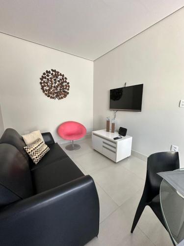 a living room with a black couch and a red chair at Casa para 5 pessoas - Perto de Tudo in Montes Claros