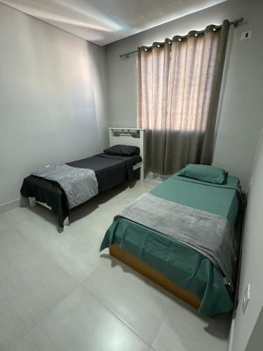 a bedroom with two beds and a window at Casa para 5 pessoas - Perto de Tudo in Montes Claros
