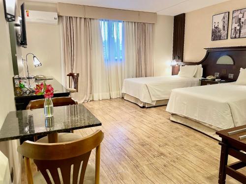 a hotel room with two beds and a table at Transamerica Executive Curitiba Batel in Curitiba