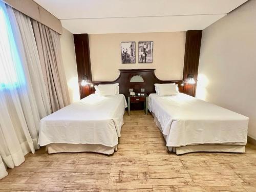 a hotel room with two beds and a window at Transamerica Executive Curitiba Batel in Curitiba
