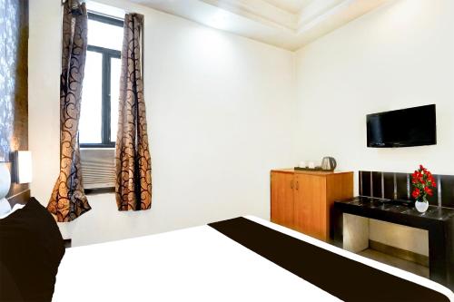 a bedroom with a bed and a tv and a window at Super Collection O Banipark Formerly Arena Villas in Jaipur