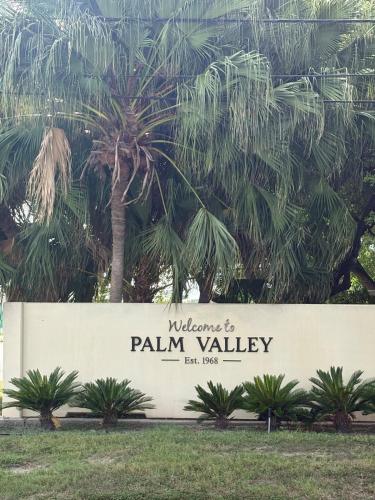 un signe devant un palmier dans l'établissement Palm Valley Country Club Getaway, à Harlingen