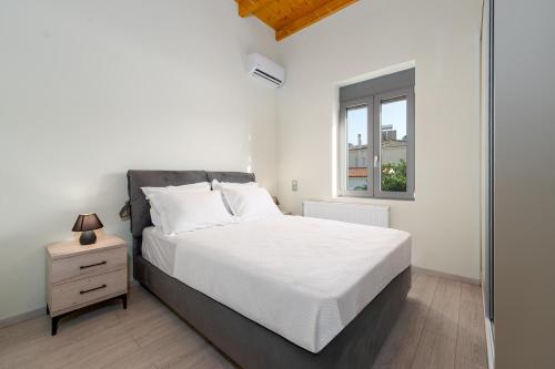a white bedroom with a bed and a window at Porto & Mare Elegant Suites in Diakopto