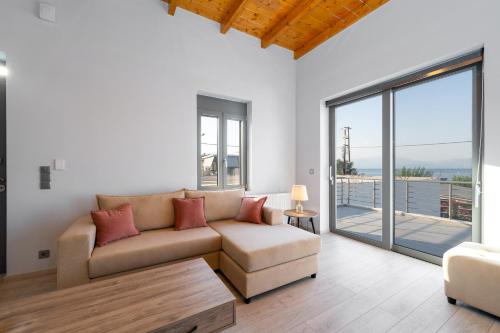 a living room with a couch and a large window at Porto & Mare Elegant Suites in Diakopto