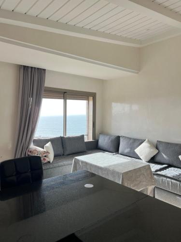 a living room with a couch and a large window at Résidence 7 vagues in Oualidia
