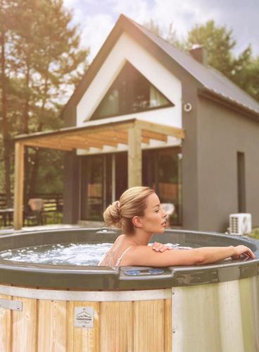 a woman in a hot tub in front of a house at Osada pod Gwiazdami & SPA - FAMILY ogrodzony dom, prywatne JACUZZI, kominek, grill, ognisko, Kajaki, Plaża, Jeziora in Łasko