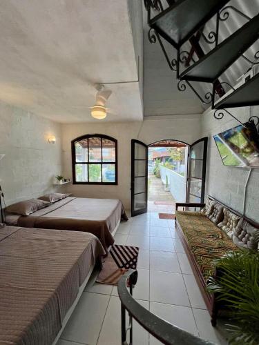 a bedroom with two beds and a hallway with windows at Casa estilo chale dúplex com 3 quartos, churrasqueira, balanço, chuveirão e a uma quadra da praia in Mangaratiba