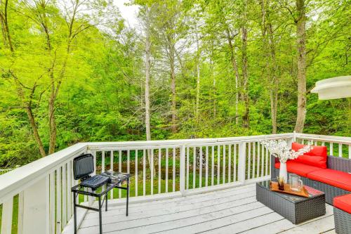 a deck with a red couch and a table at Serene Duplex with On-Site Brook in Callicoon Center in Roscoe