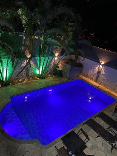 a swimming pool at night with blue lights at Brisa mar pousada in Ubatuba